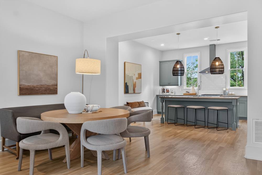 Round dining table with open kitchen and blue-gray island beyond, real estate photography in metro Atlanta