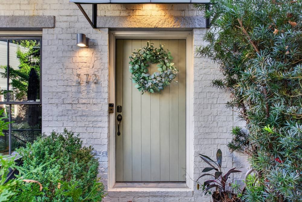 Sage green front door with wreath on painted white brick, real estate photography in Decatur, GA