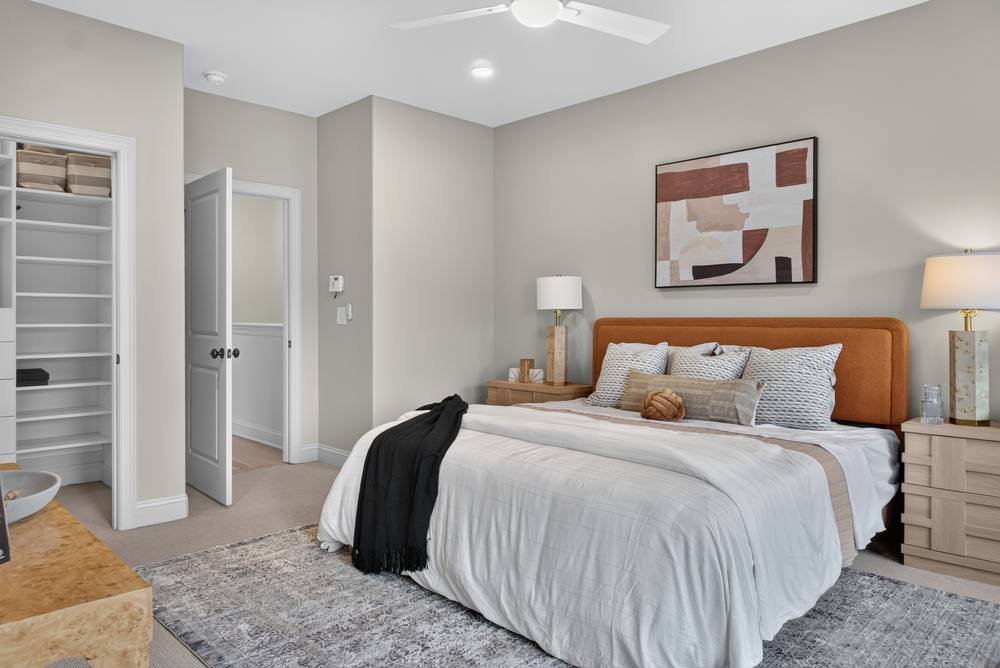 Staged primary bedroom with walk-in closet and orange headboard, real estate photography in metro Atlanta