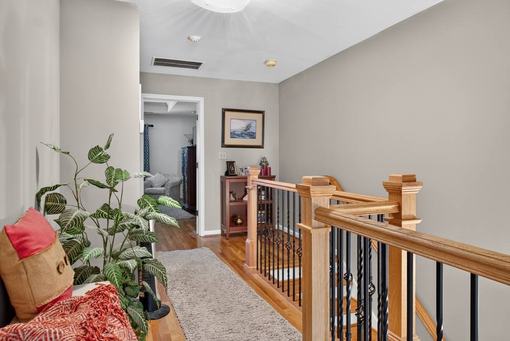 Upstairs hallway with wood railing and hardwood floors, real estate photography in Decatur, GA