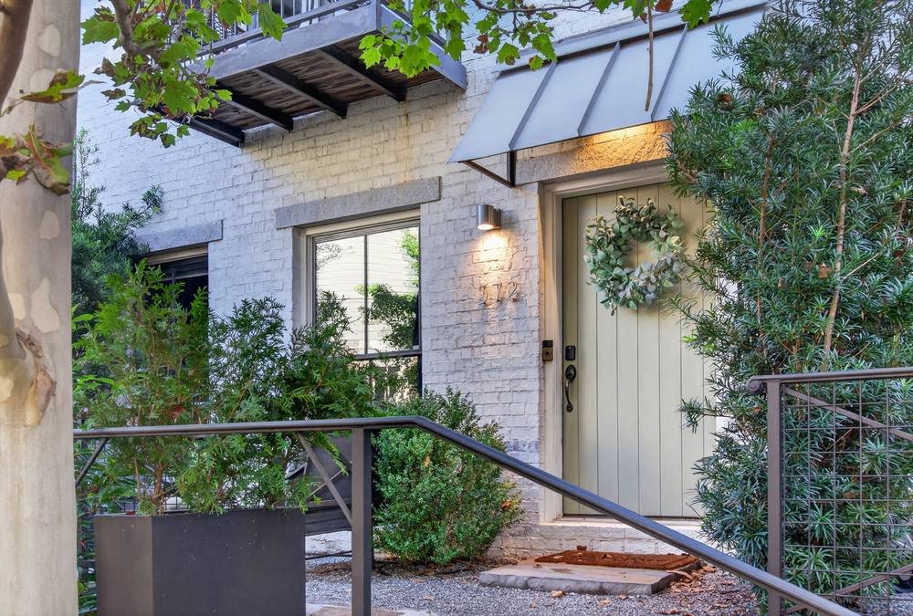 Front entry of a white brick home with metal awning and lush plants, real estate photography in Conyers, GA